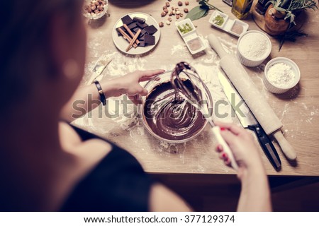 Cake making, preparation.Preparations for making homemade chocolate.Mixed ingredients prepared for baking cake or bake.A whisk in a round bowl with liquid chocolate.Housewife making a chocolate cake
