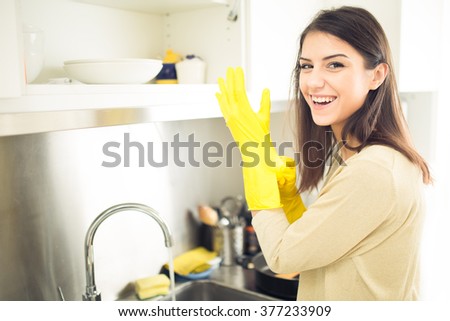 Hand cleaning.Young housewife woman washing dishes in kitchen.Preparing to clean,funny smiling photo with yellow rubber gloves.Smiling young beautiful brunette cleaning kitchen