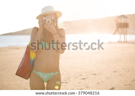 Attractive fit trendy modern hipster woman taking photos with retro vintage film camera.Lifestyle photographer.Summer beach woman taking picture during summer holiday vacation travel.Sexy cool hipster