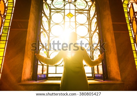 Religious christian woman looking trough the stained glass church window light.Woman praying to god at St. Alexander Nevsky Cathedral.Christianity.Strong religion,faith and hope concept.Enlightenment