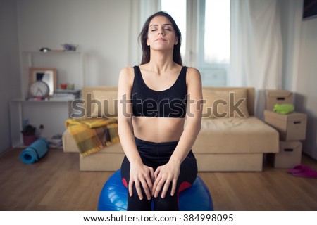 Carefree calm woman meditating.Enjoying peace and serenity.Living room for after work relaxation and meditation.Having a deep breath.After work out relaxation of muscles and breathing exercises