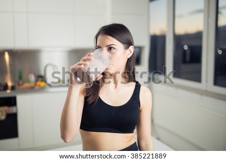 Woman in sportswear  drinking sweet banana chocolate protein powder milkshake smoothie.Drinking protein after workout.Whey,banana and low fat milk sport nutrition diet after gym.Healthy lifestyle