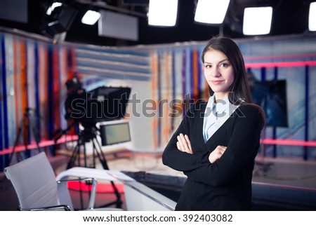 News writing and reporting.Woman journalist in television studio standing with her arms crossed.Determination,journalistic fairness and accuracy.Interview talk show with live audience.Media industry