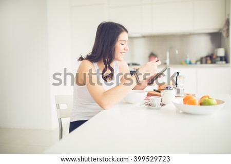 Young smiling woman eating healthy breakfast and smiling.Starting your day.Dieting,fitness and well being.Positive energy emotion.Productivity,happiness,enjoyment concept.Morning ritual.Technology