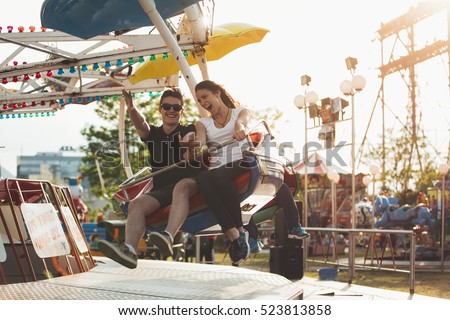 Brother and sister having a ride at an amusement park. Spending free time together. Bonding and entertainment concept.Beautiful sunset at theme park in summer holiday vacation.