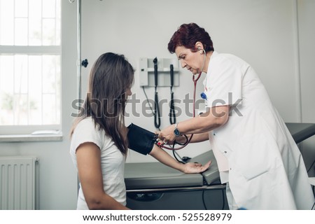 Nurse measuring her patient\'s heart pressure. Interacting and taking care of patient. Taking care of your health. Disease prevention.