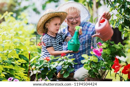 Gardening with kids. Grandmother and her grandchild enjoying in the garden with flowers. Hobbies and leisure, lifestyle, family life