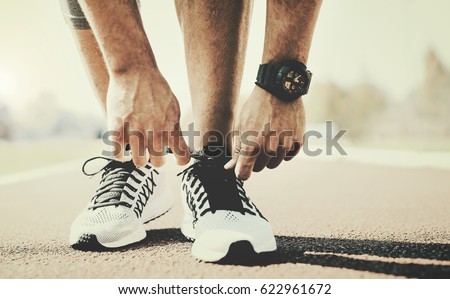 Tying sports shoe. A young sportsman getting ready for athletic and fitness training outdoors. Sport, exercise, fitness, workout. Healthy lifestyle