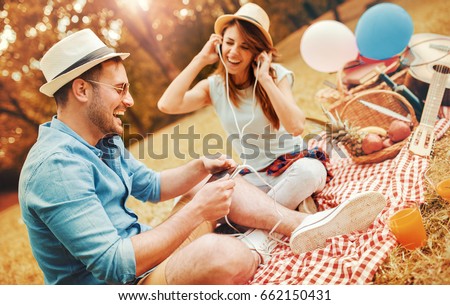 Picnic time. Young couple listening to music during picnic in the park, having fun together. Love and tenderness, dating, romance, lifestyle concept