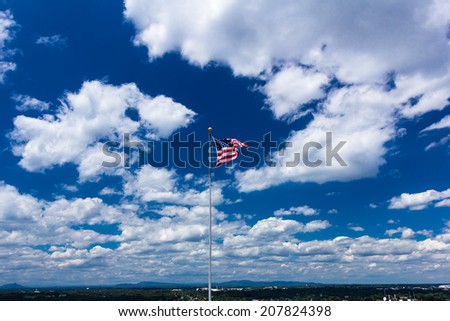 American flag against blue sky with mountains in the background.