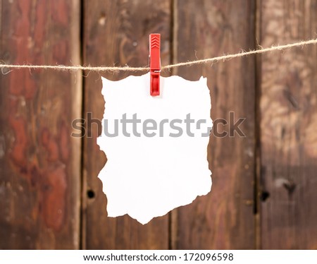 White empty paper note hanging on clothesline, on old wood background