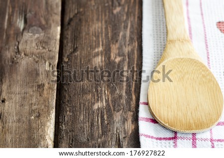 Wooden kitchen spoon on a red and white napkin on a wooden tabletop with copyspace