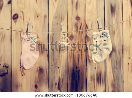 Baby girl socks and nipple on the clothesline. Vintage filter.
