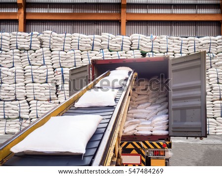 White bags of sugars from warehouse are staffing in container for export.