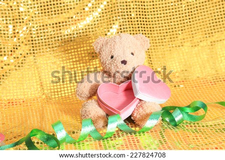 bear toy and gift box on gold glitter background
