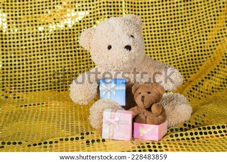 teddy bear toy on gold glitter background with gift box