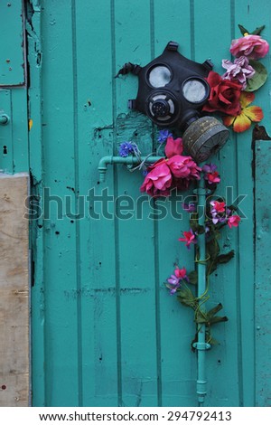 Gas mask and artificial flowers on the old wooden door