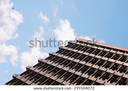 Close-up of facade of office building with flying dove in the sky.