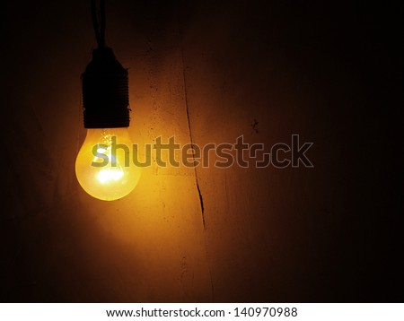 Dusty Incandescent light bulb on a dark wall background.