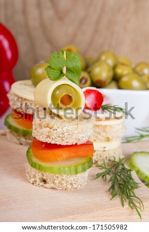 finger foods: bread, peppers, cucumber, cheese and olives on white wooden table