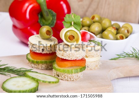 finger foods: bread, peppers, cucumber cheese and olives on white wooden table