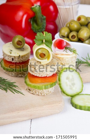 finger foods: bread, peppers, cucumber, cheese and olives on white wooden table