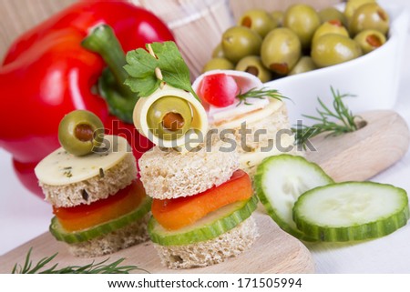 finger foods:  bread, peppers, cucumber, cheese and olives on white wooden table