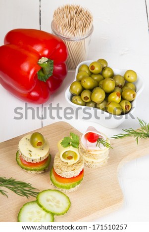 finger foods : bread, peppers, cucumber cheese and olives on white wooden table