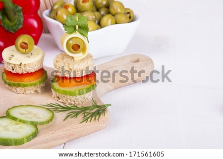 finger foods: bread, peppers, cucumber cheese and olives on white wooden table