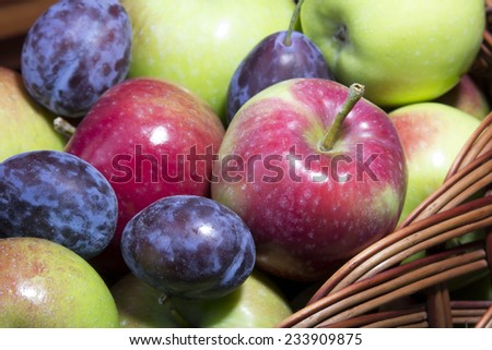 fresh plums and apples in a wicker basket