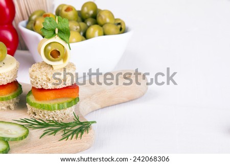 finger foods made of bread, peppers, cucumber cheese and olives on wooden table