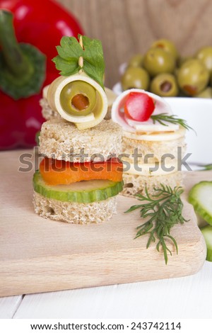 finger foods made of bread, peppers, cucumber cheese and olives on wooden table