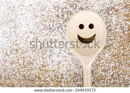 Spoon with smile on the wooden pastry board - baking background