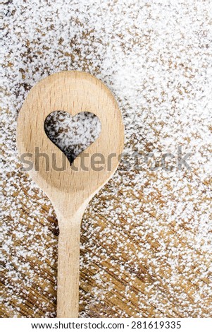 Heart hole spoon on the wooden pastry board - baking background