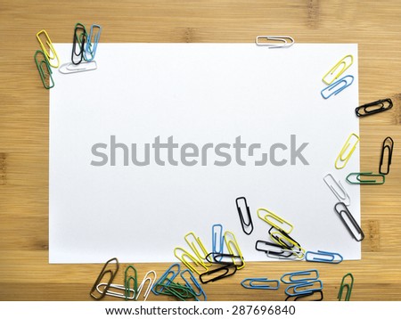 paper clips and blank paper on wooden background