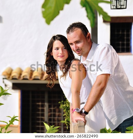 Young couple dressed in white love caught in the railing of a balcony in a cottage