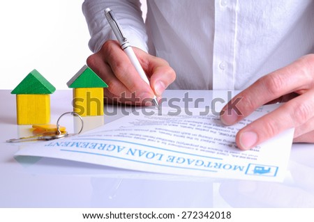 client signing the mortgage loan agreement for the purchase of a new home with small wooden houses rear view