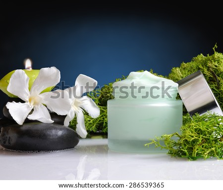 Glass cream jar open algae. Flowers, black stones and seaweed decoration. Windows background. Front view