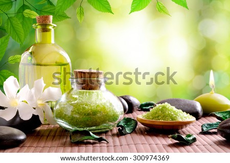 Bath salts and body oil on wooden mat. Nature leaves and bokeh background. Horizontal composition
