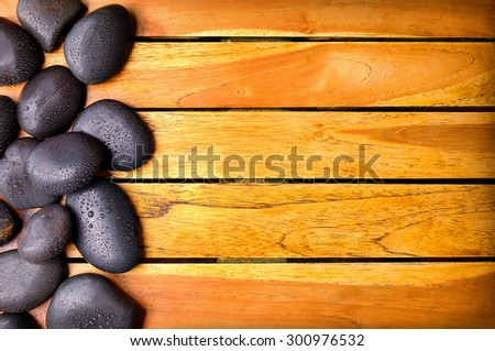 Black stones with water drops on the left side on wooden slats. Sauna and massage concept. Horizontal composition. Top view