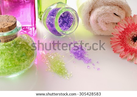 Oils and bath salts on white glass table. Decorated with flower and towel. Horizontal composition