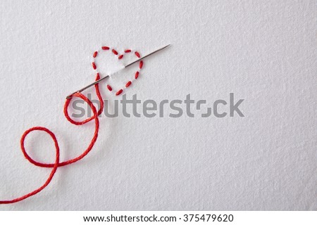 Embroidered red heart on a white cloth.  Concept passion for sewing and embroidery. Horizontal composition.Top view