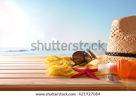 Beach articles on a table wooden slats and sea background with sunbeam. Horizontal composition. Front view.