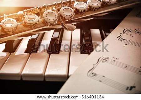 Piano and flute with golden shine and sheet music. Horizontal Composition.Front view