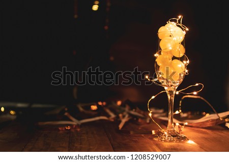 End of the year concept. Glass of champagne with grapes inside, with holiday decoration