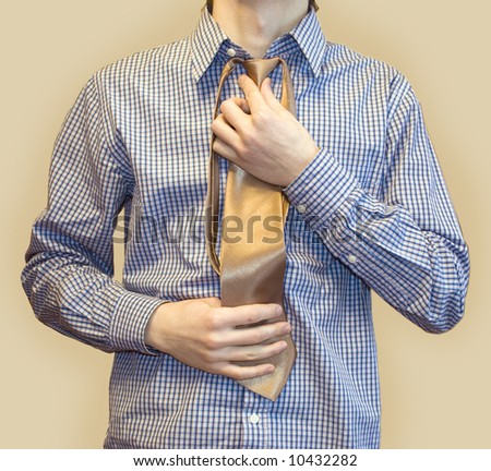 Young man trying on blue shirt and golden tie in fitting room on white background isolated