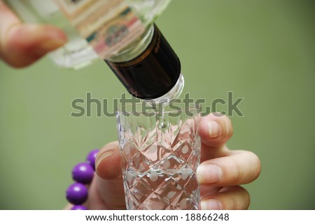Girl\'s hand with russian vodka bottle and glass retro style on green background