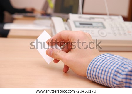 Man in blue shirt giving visit card to nobody telephone and office on background