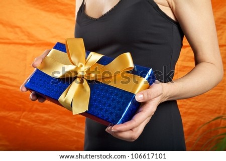 black dressed woman holding a blue gift package