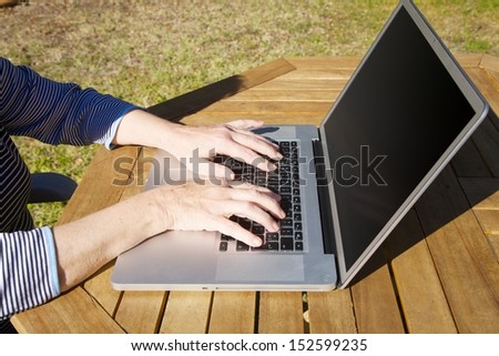 hands of old woman tapping on portable computer